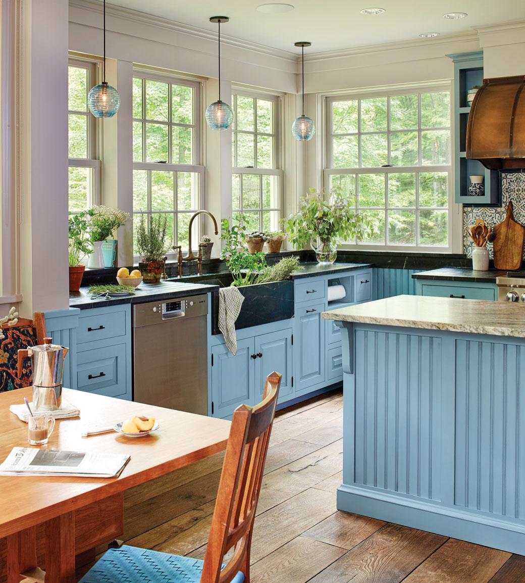 Bright blue farmhouse kitchen with apron sink and plants by CrownPoint