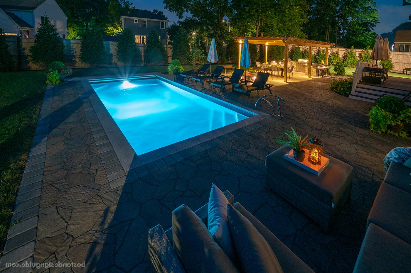 Residential pool terrace design at night by Land Design Associates